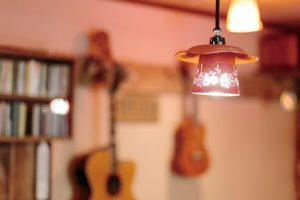 ランプに照らされたあたたかな雰囲気のカフェ店内。壁にはギターなど楽器がかかっている。